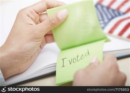 Human hands holding adhesive note with I voted text