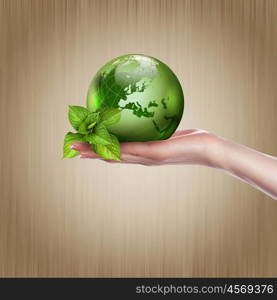 human hands holding green earth with a growing plant