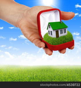 human hands holding model of a house against nature background