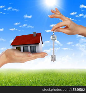 human hands holding model of a house against nature background