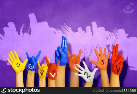 Human hands in colorful paint showing symbols