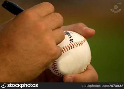 Human hands signing on ball, close-up