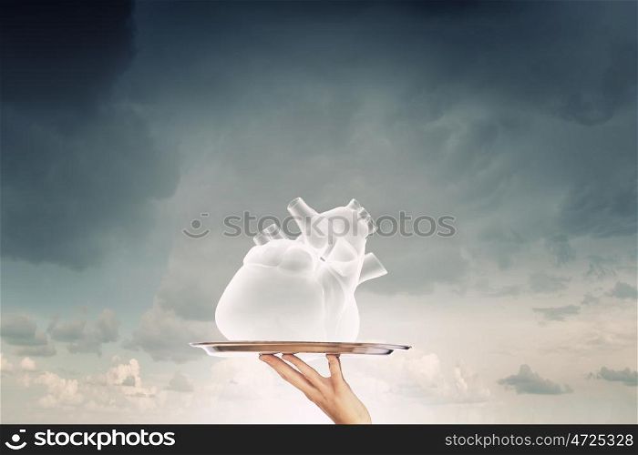 Human heart on tray. Hand holding tray with human heart sign on cloud background