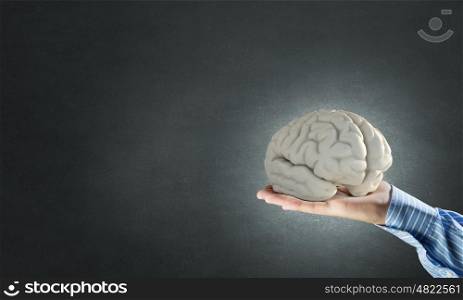 Human mind concept. Close up of businessman holding image of brain in hands
