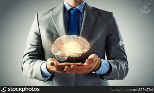Human mind research. Close up of businessman hands holding brain in palm
