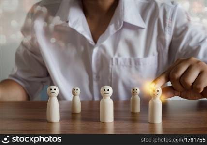 Human resources and recruiting business or team leader management concepts. Hand adult Asian man holding of people icon leadership community on wooden doll. HR Human employee, social networking,