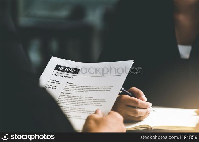 Human resources department manager reads CV resume document of an employee candidate at interview room. Job application, recruit and labor hiring concept.