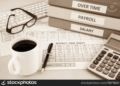 Human resources documents: payroll, salary and employee time sheets place on office table with cup of coffee and calculator, sepia tone