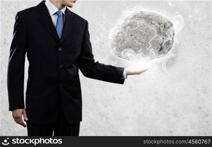 Human strength and power. Businessman in suit huge holding stone in palm