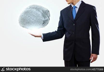 Human strength and power. Businessman in suit huge holding stone in palm
