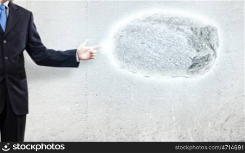 Human strength and power. Businessman in suit pointing at huge stone