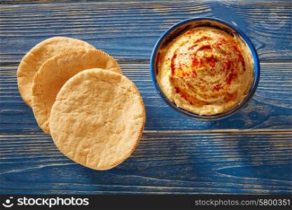 Hummus with pita bread and red pepper powder on blue Mediterranean wood table