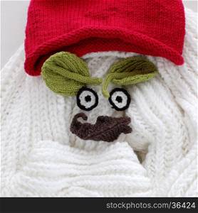 Humor eyes of winter make from yarn, diy simple background for Xmas holiday by knitted leaf for eyebrow, nose on white scarf background, joyful craft with funny face
