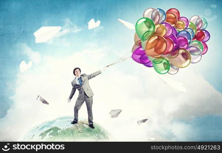 Humorous guy with balloons. Funny man in suit with bunch of colorful balloons in hand