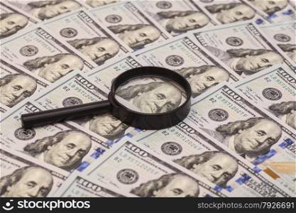 Hundred dollar banknote under magnifying glass