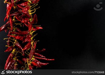 Hungarian paprika pepper string, black background, copy space on right, landscape, closeup