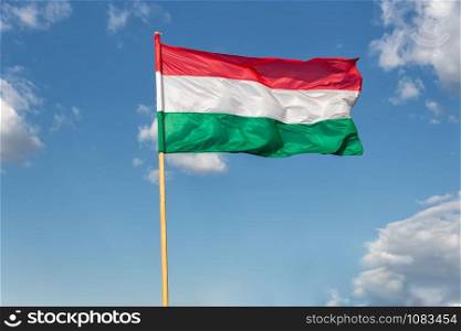 Hungary national flag waving on the wind on blue sky backgroundwith white clouds. Hungary national flag waving on wind at blue sky background