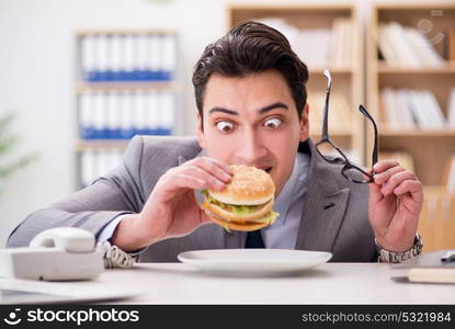 Hungry funny businessman eating junk food sandwich