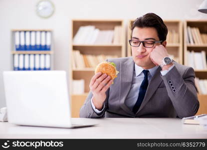 Hungry funny businessman eating junk food sandwich