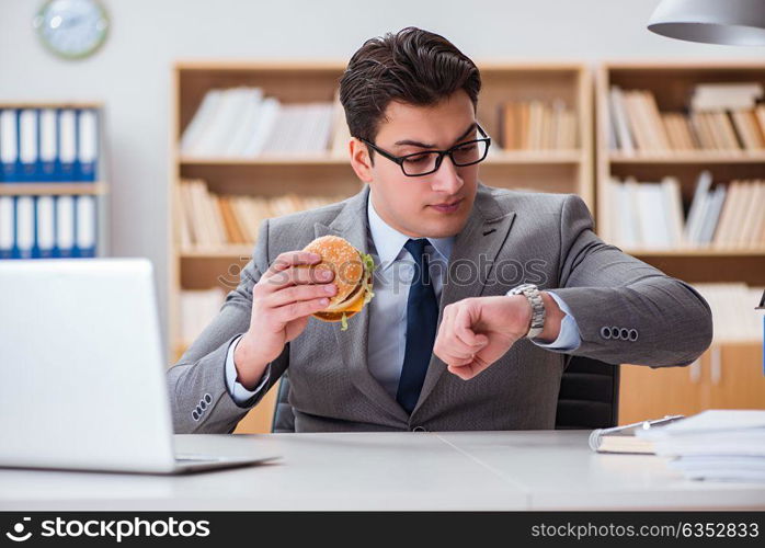 Hungry funny businessman eating junk food sandwich