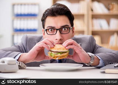 Hungry funny businessman eating junk food sandwich