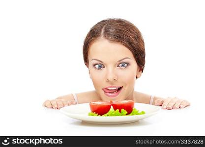 Hungry girl looks out from under table on plate with vegetables, isolated