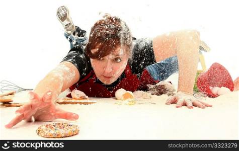 Hungry teen girl diving through baking mess to get the last sugar cookie.