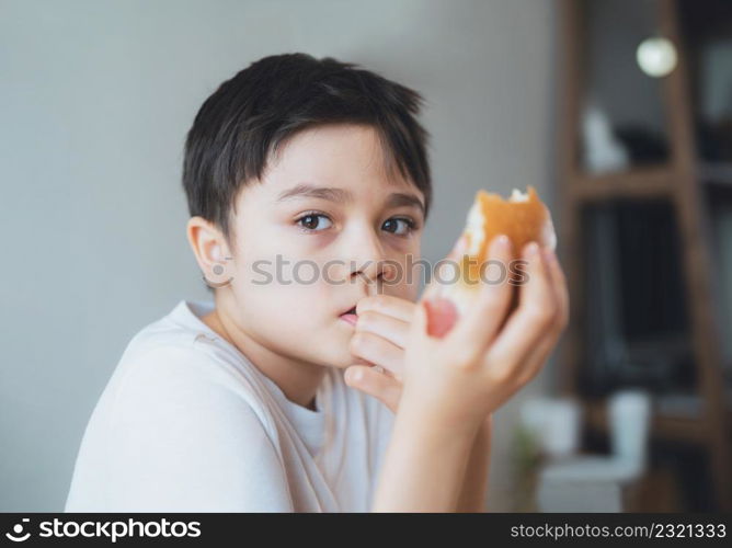 Hungry young boy eating homemade bacon sandwiches with mixed vegetables, Healthy Kid having breakfast at home, Child bitting finger nails and looking out with thinking face