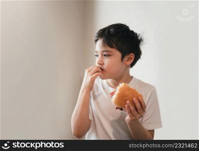 Hungry young boy eating homemade bacon sandwiches with mixed vegetables, Healthy Kid having breakfast at home, Child bitting finger nails and looking out with thinking face