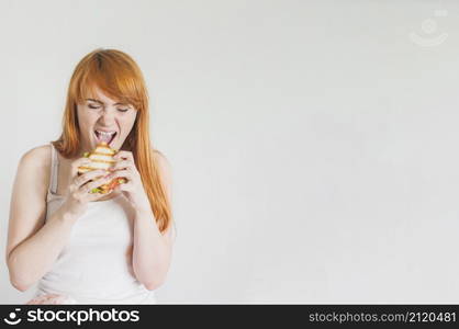 hungry young woman eating grilled sandwich against white background