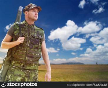 hunting, army, military service and people concept - young soldier, ranger or hunter with gun over natural background and blue sky. young soldier or hunter with gun over savannah