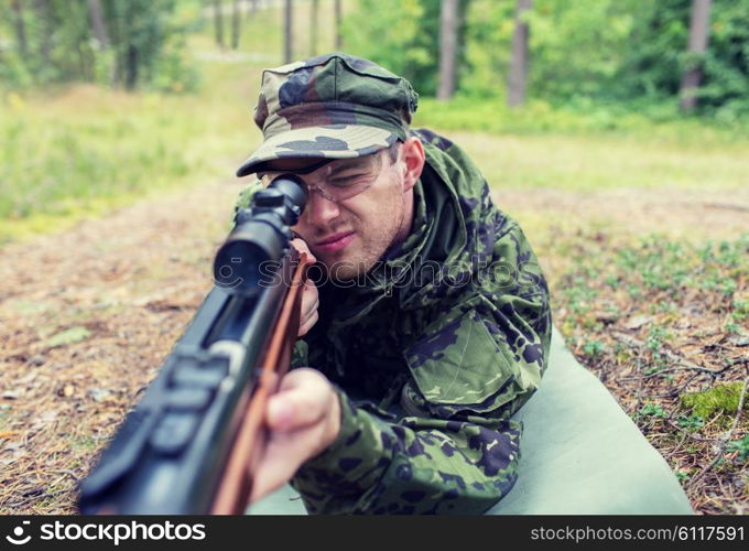 hunting, war, army and people concept - close up of young soldier, ranger or hunter with gun in forest