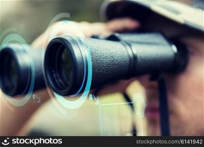 hunting, war, army and people concept - close up of young soldier looking to binocular with virtual hologram and observing forest