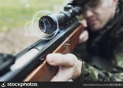 hunting, war, army, technology and people concept - close up of young soldier or sniper holding gun with virtual screen projection and aiming in forest