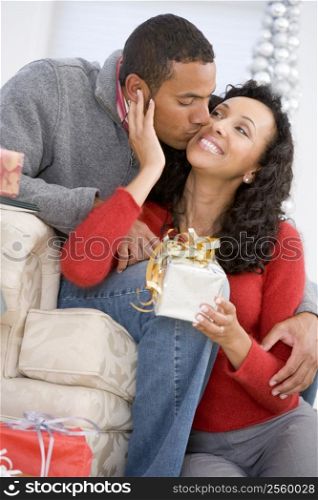 Husband And Wife Affectionately Exchanging Christmas Gifts