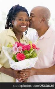 Husband and wife holding flowers kissing and smiling