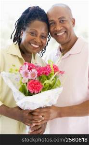 Husband and wife holding flowers smiling