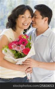 Husband and wife holding flowers smiling