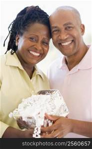 Husband and wife holding gift smiling