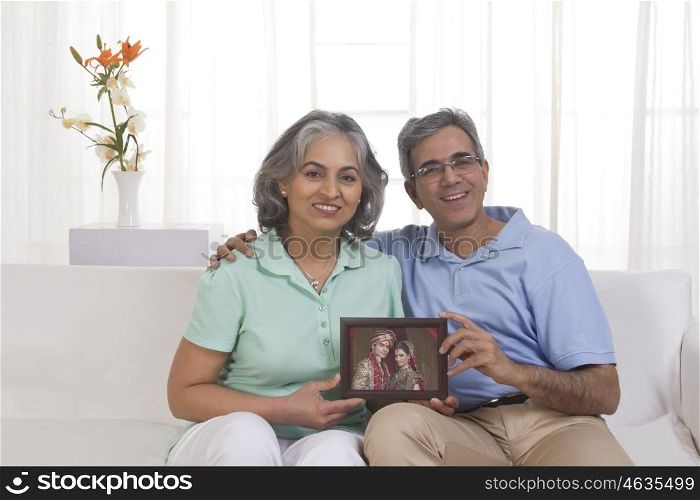 Husband and wife holding picture of their children