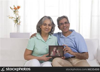 Husband and wife holding picture of their children