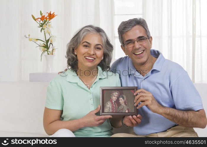 Husband and wife holding picture of their children