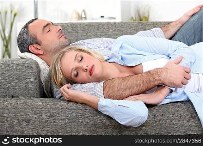Husband and wife sleeping on their couch