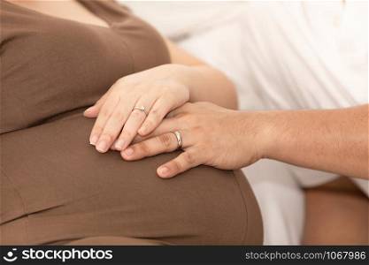 husband and wife take their hands and hold their stomachs while pregnant while giving birth and baby love care concept to selective focus
