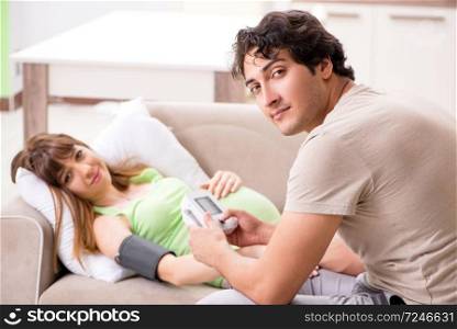Husband checking pregnant wife&rsquo;s blood pressure