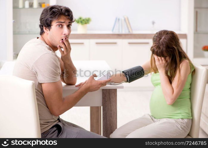 Husband checking pregnant wife&rsquo;s blood pressure