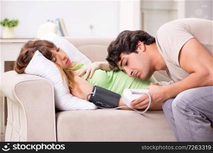 Husband checking pregnant wife&rsquo;s blood pressure. The husband checking pregnant wife&rsquo;s blood pressure