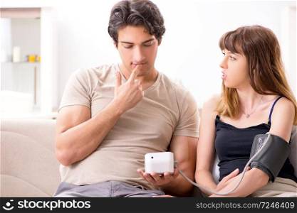 Husband checking wife&rsquo;s blood pressure. The husband checking wife&rsquo;s blood pressure