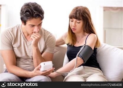 Husband checking wife’s blood pressure