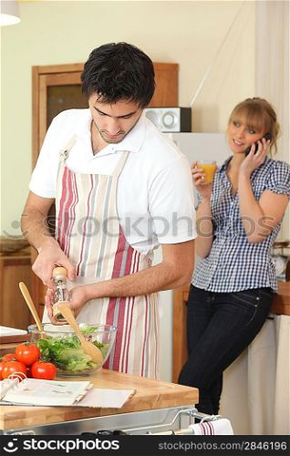 Husband cooking whilst wife telephones